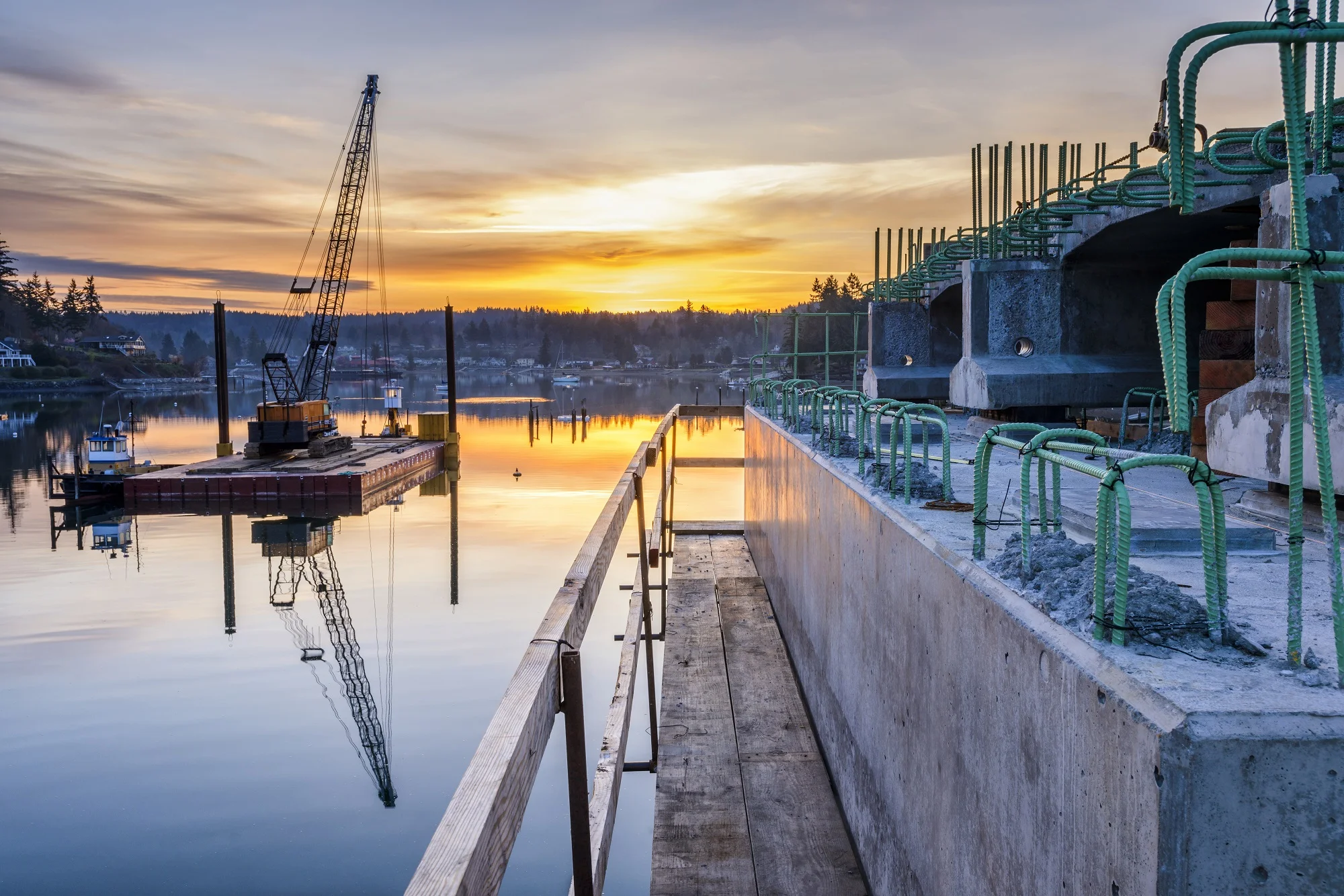 Reflection of bridge construction and sunset in still bay